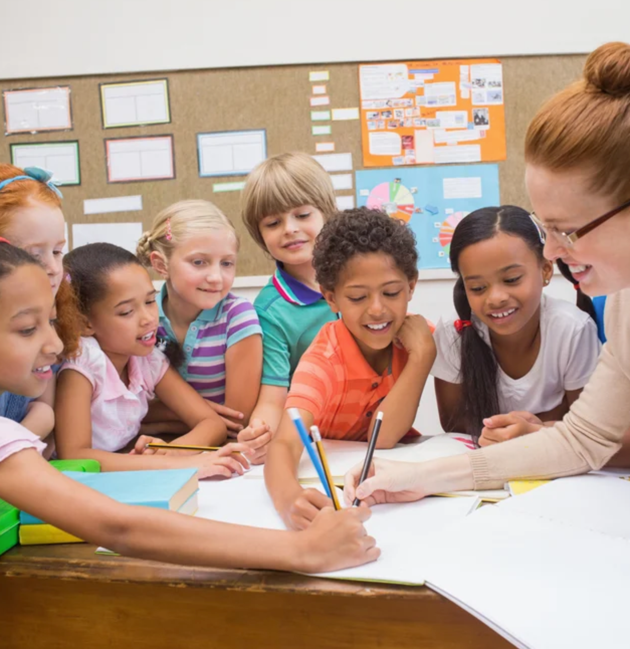 Teacher_and_pupils_working_at_desk_together_at_the_elementary_school_jpeg__1000×667_-1
