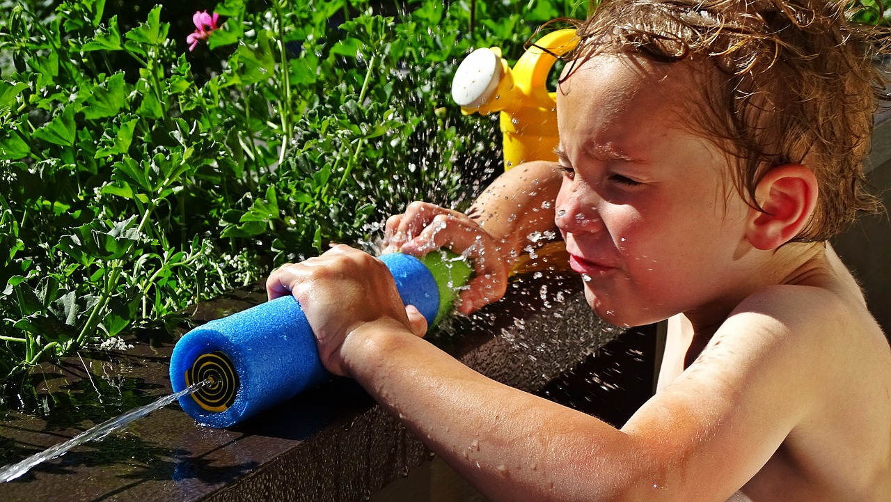 A young boy squirts water from a water gun in the sun