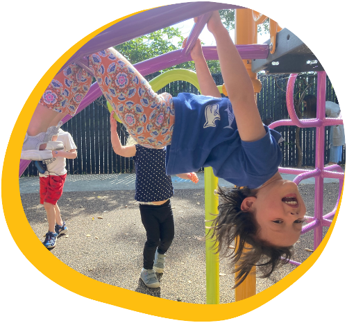 female preschool student at kids konnect redwood city hanging upside down on the jungle gym